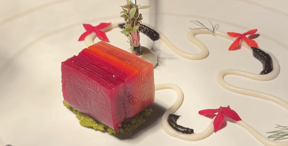Gourmet dish with layered terrine, sauce, and floral garnish